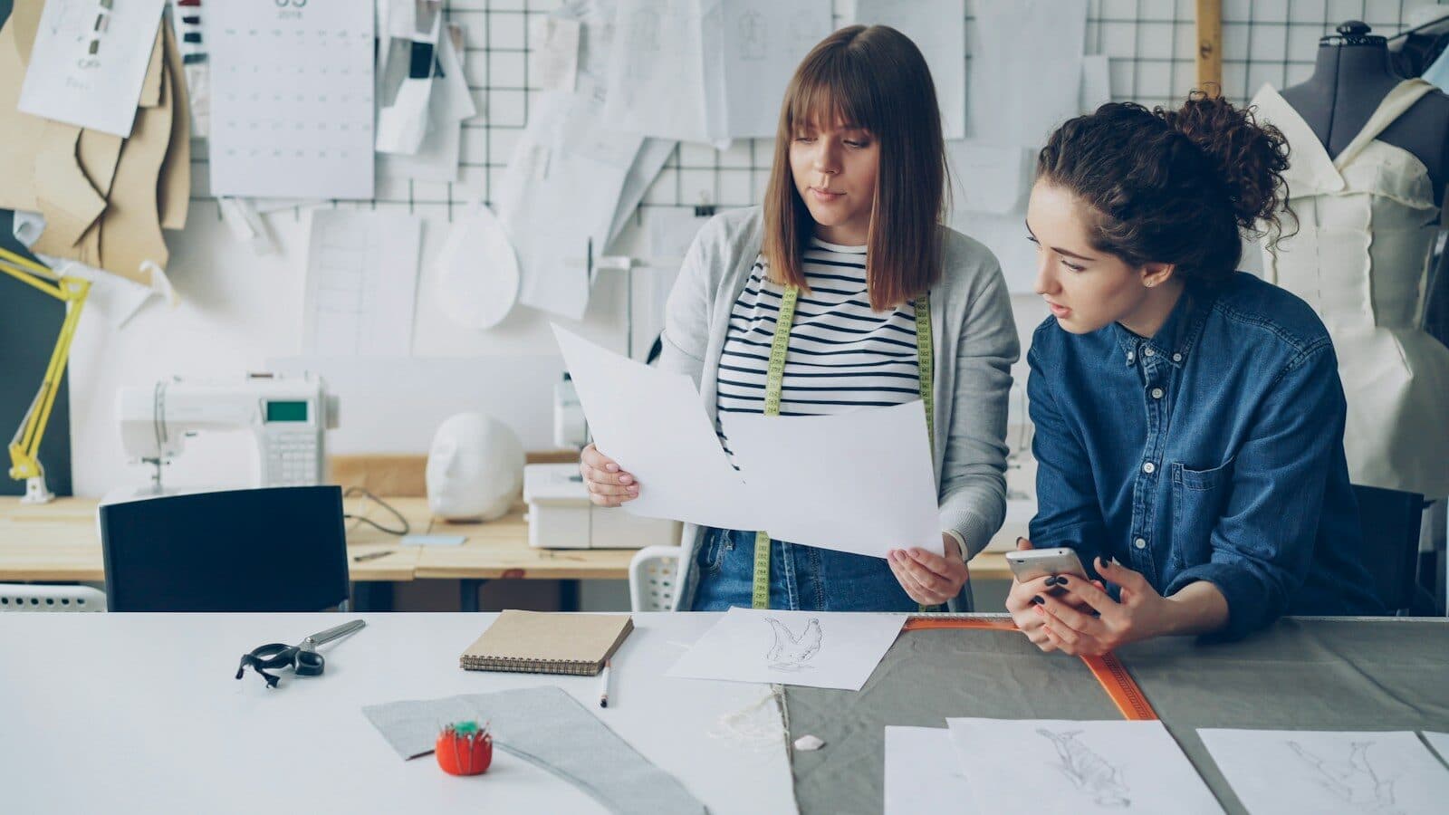 Two women discuss designs in a workshop